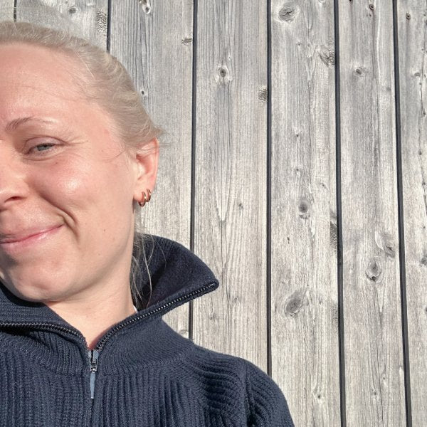 Marie lächelt vor einer Holzwand in Dänemark