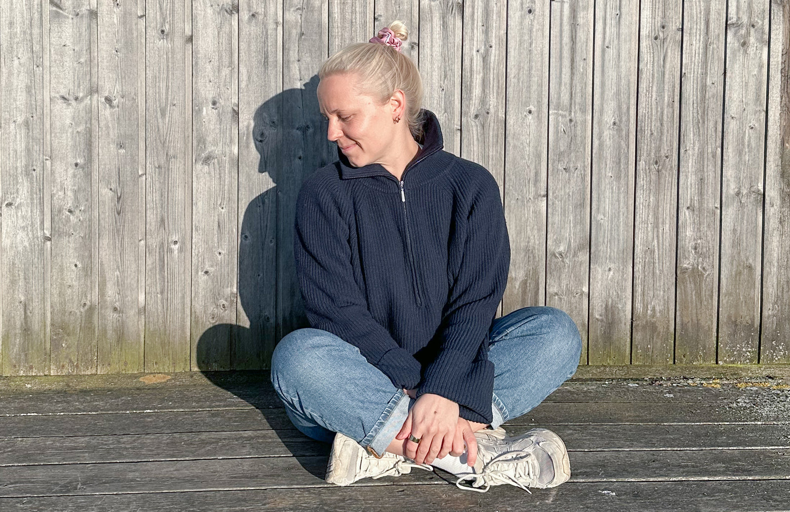 Marie sitzt in der Sonne an einer dänischen Holzwand